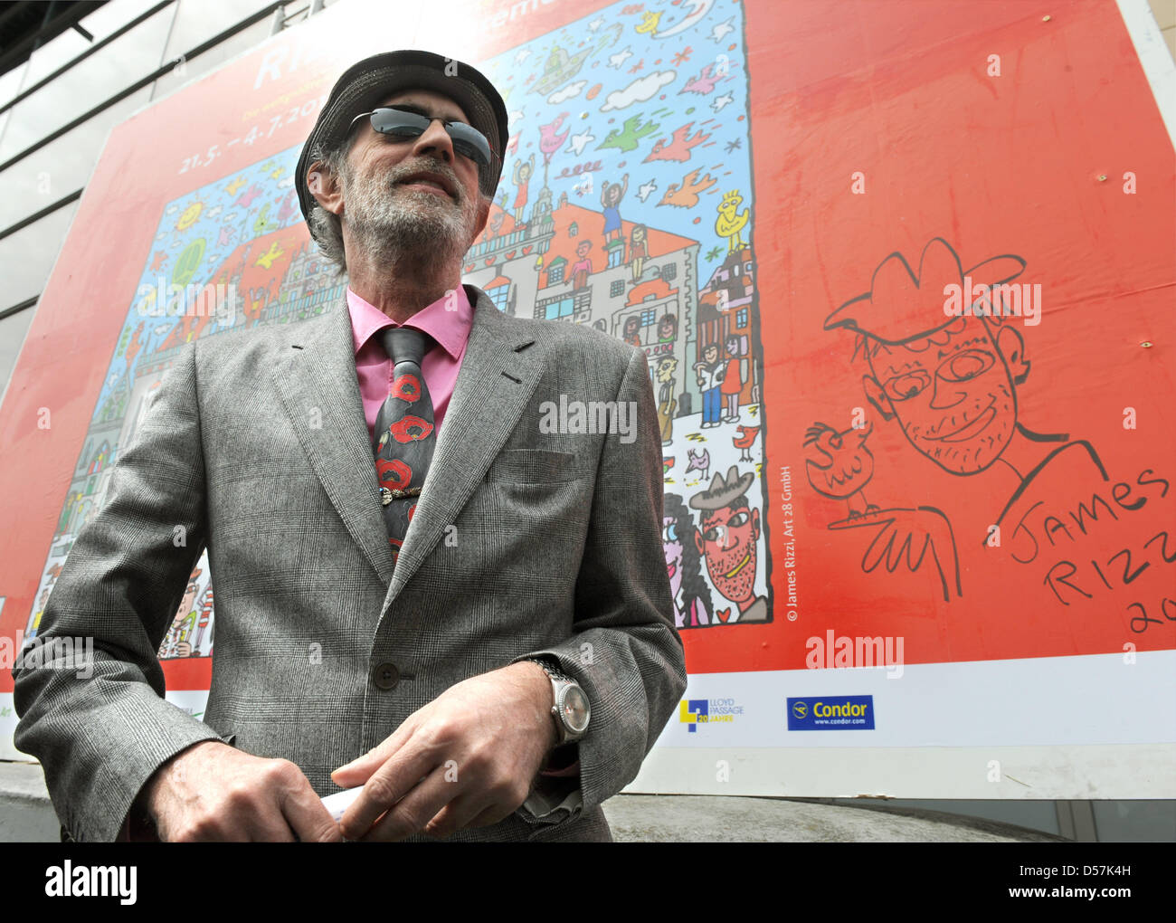 US pop art artist James Rizzi smiles in front of an advert banner for his  exhibition 'Rizzi's World' in Bremen, Germany, 20 May 2010. The exhibition  puts more than 1,200 exhibits of