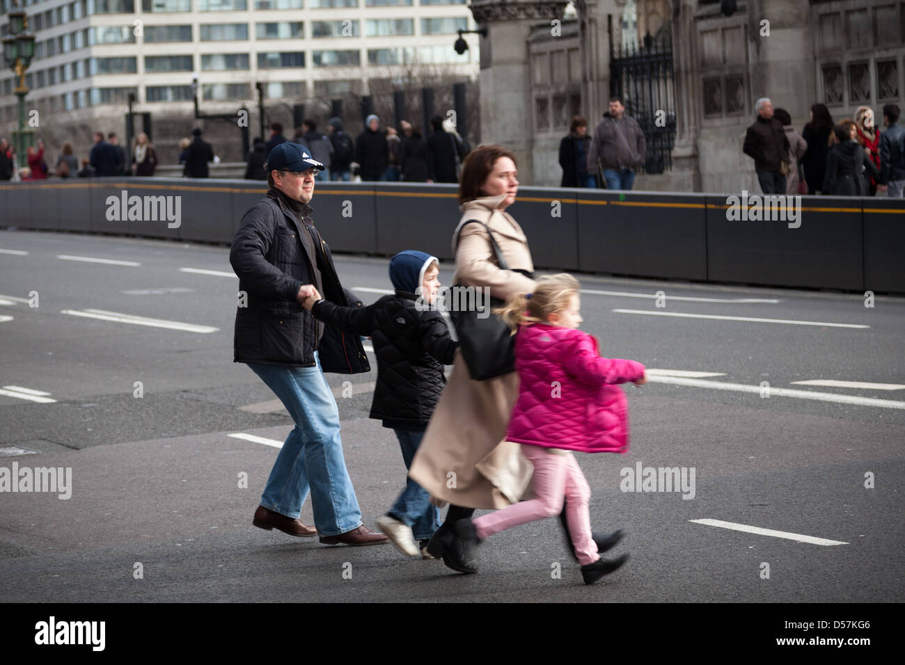 A family hesitate whilst attempting to cross a road on Westminster Bridge opposite the Houses of Parliament in London. Stock Photo