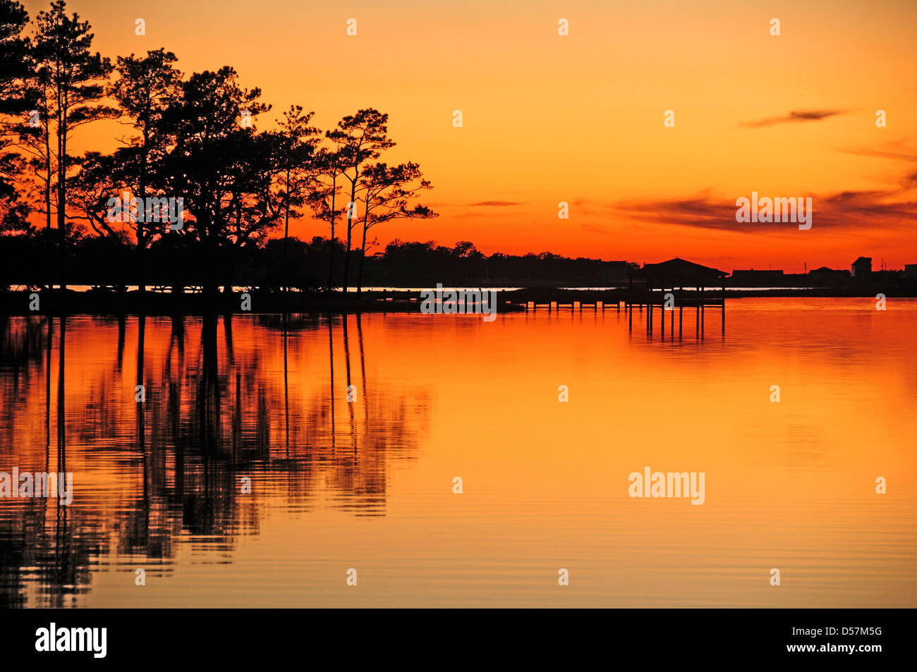 Sunset with tree reflections in calm water Stock Photo