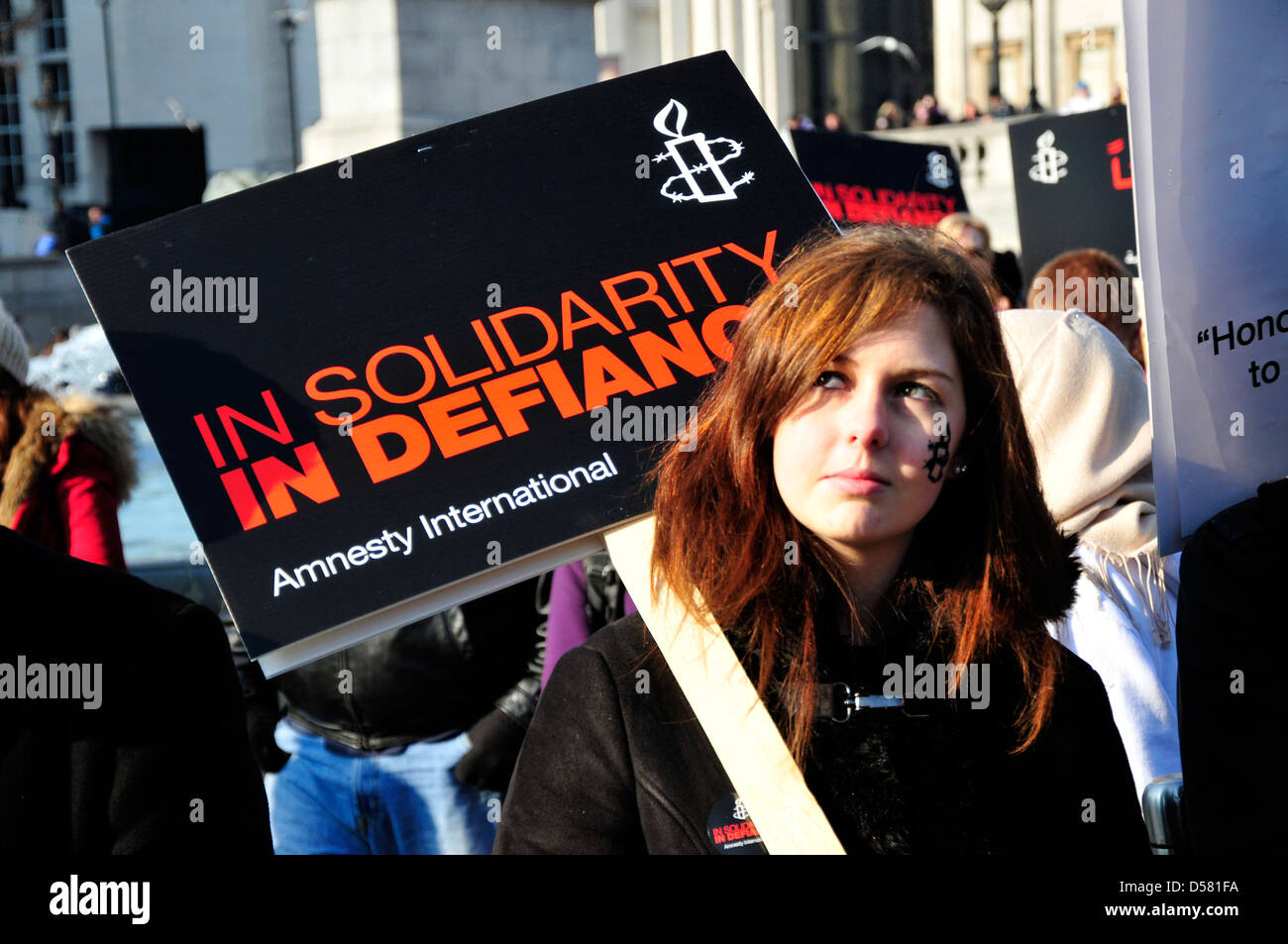 A young woman holds a banner reading ' in solidarity in defiance' at a rally in Trafalgar Square, London, UK. Stock Photo