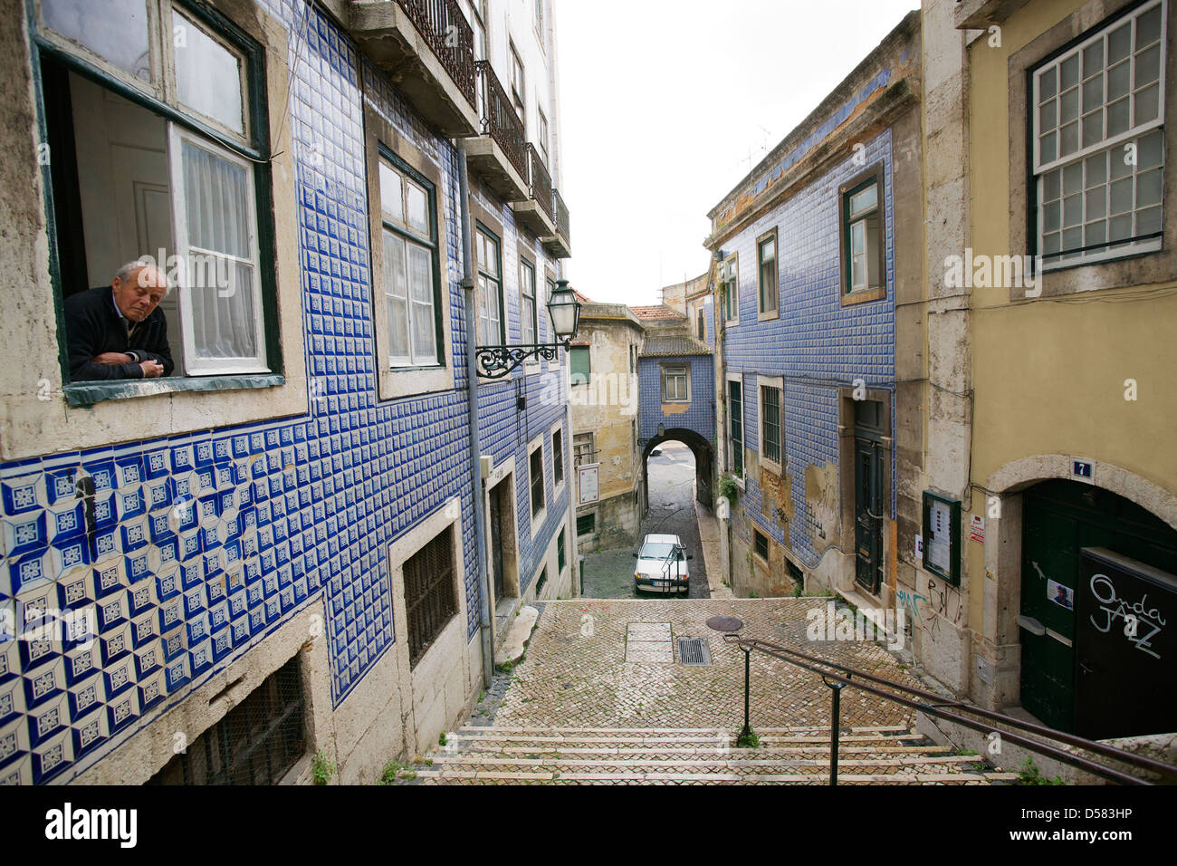 Old man looking out of a window of a building with a ceramic tiled facade in the Alfama district of Lisbon. Stock Photo