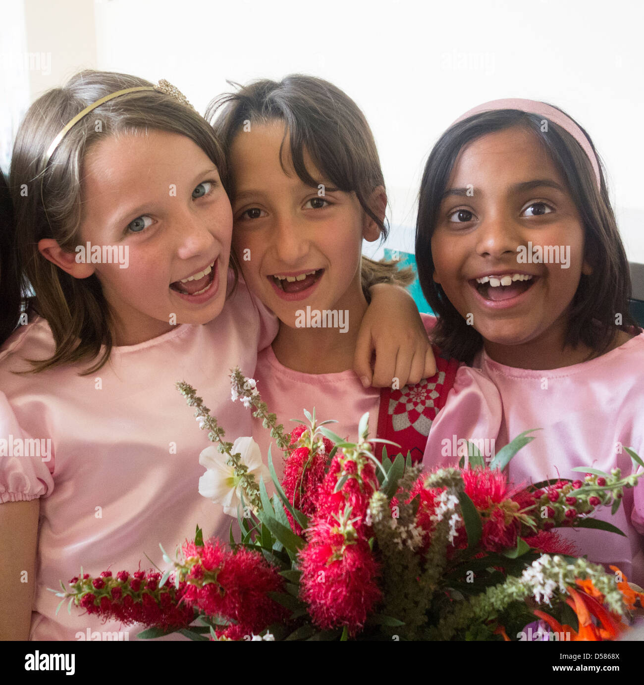 three eight year old Arab girls celebrating with flowers Stock Photo