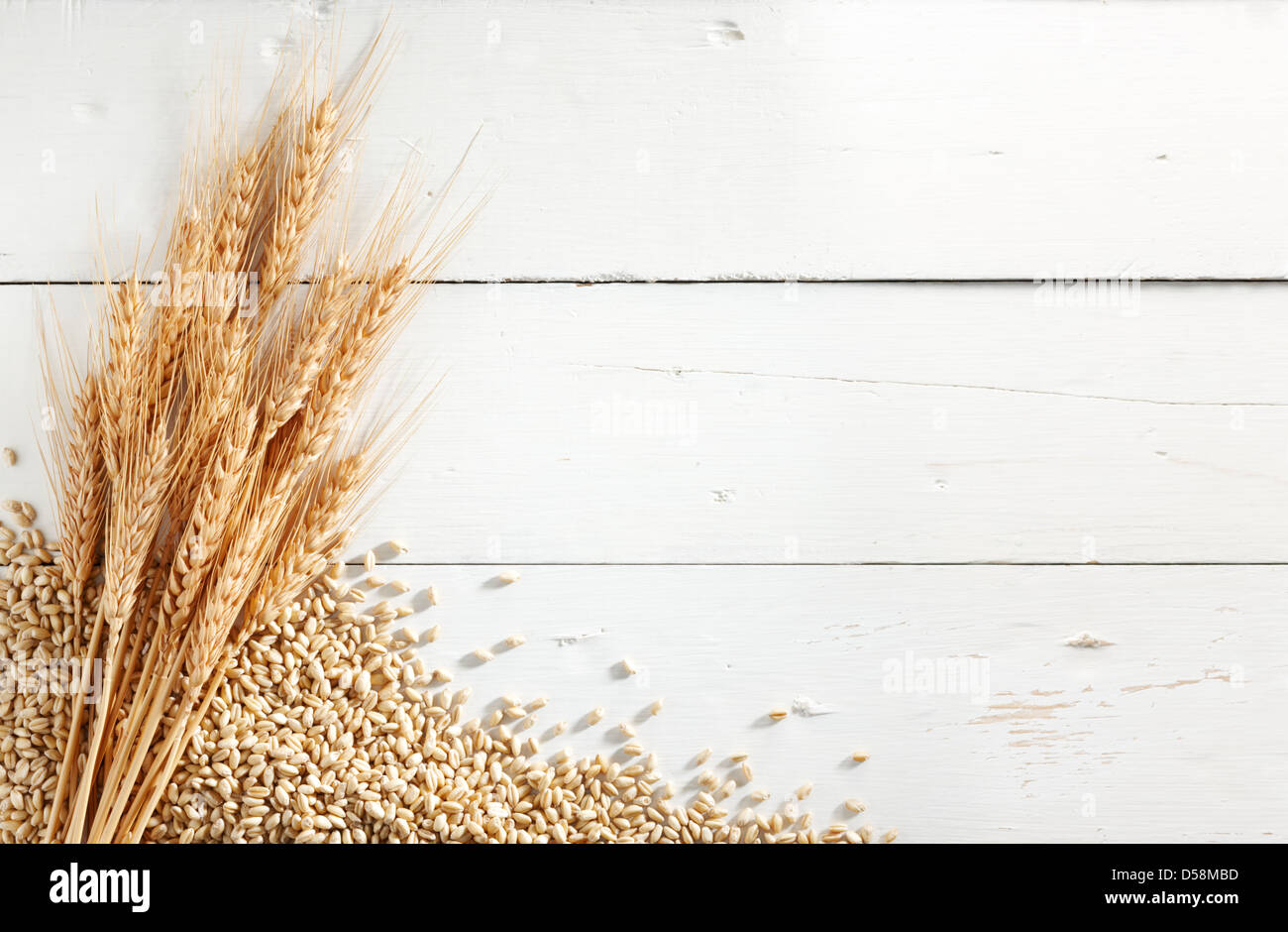 wheat ears with wheat kernels against white wood background Stock Photo