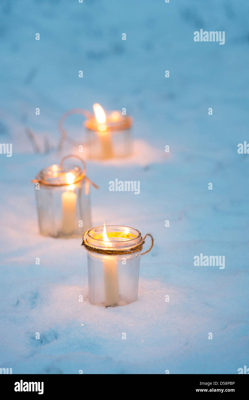 Christmas candles in glass jars in a snow covered woodland Stock Photo