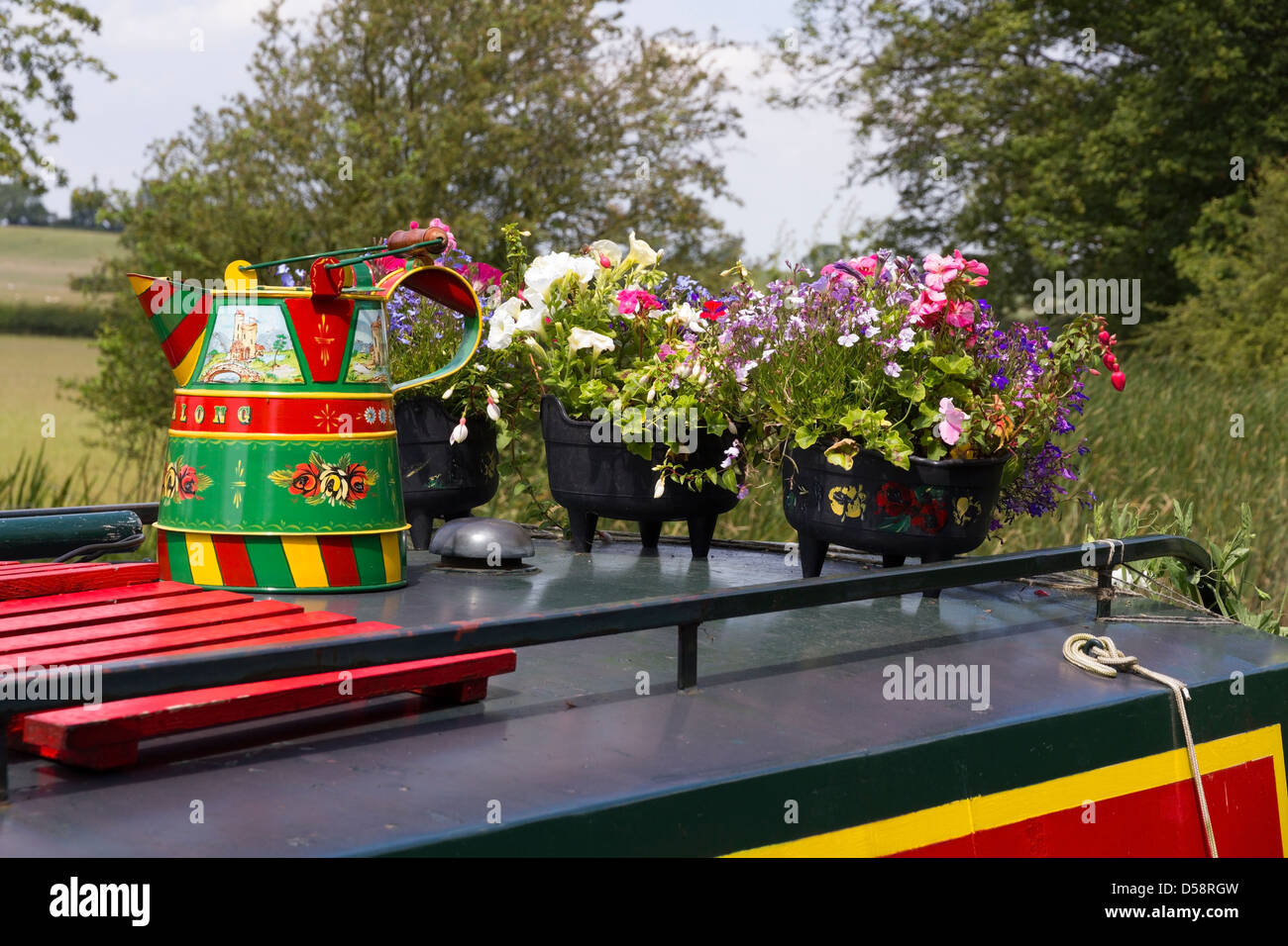 Brightly barge painted metal bucket and flowers on longboat roof, Foxton Locks, Market Harborough, Leicestershire, England, UK Stock Photo