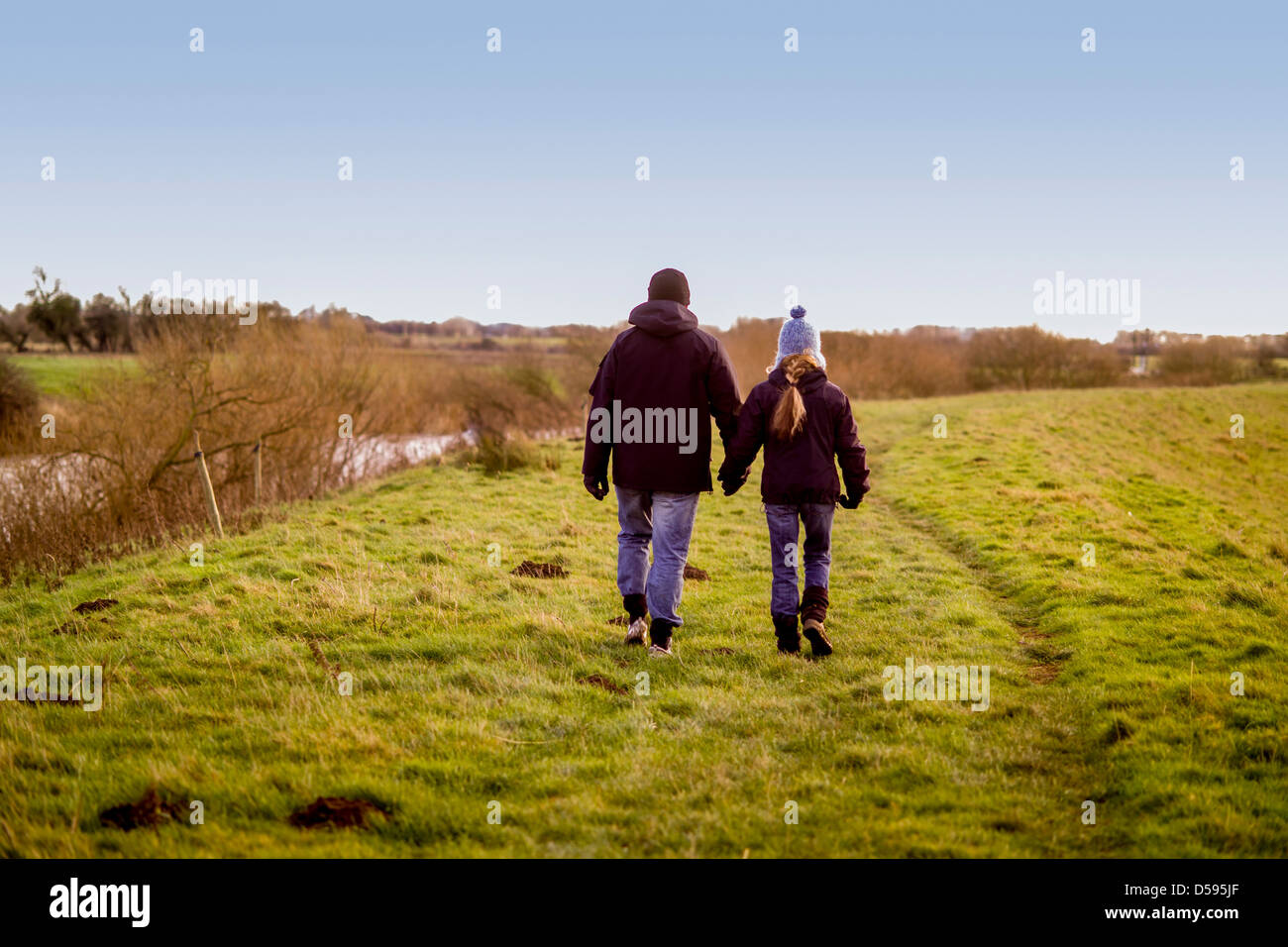 Rear view of a couple hand in hand walking away from camera in ...