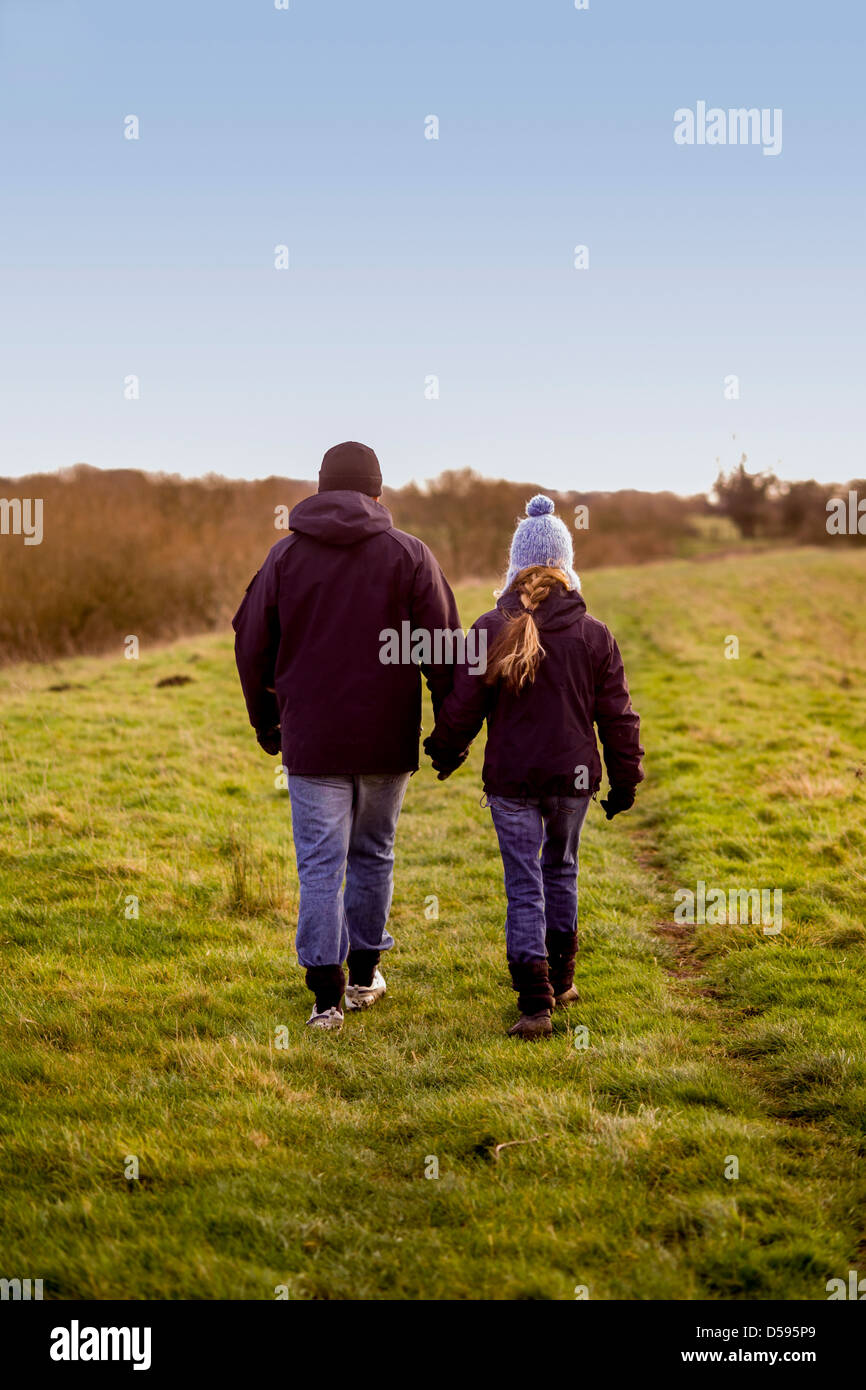 Rear view of a couple hand in hand walking away from camera in ...