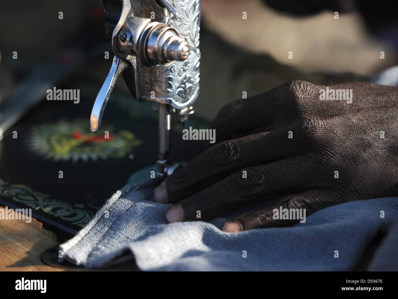 A man uses a sewing machine in the Atteridgeville Township, near Pretoria, South Africa 12 June 2010. South Africa hosts the 2010 FIFA World Cup from 11 June - 11 July for the first time on African soil. Photo: Marcus Brandt dpa Stock Photo
