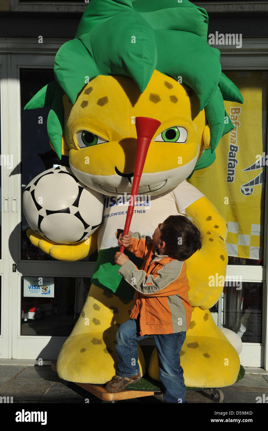 A young boy with a vuvuzela, a horn similar to a trumpet and symbol of South African soccer, stands in front of Zakumi, the leopard mascot of the FIFA World Cup 2010, in Cape Town, South Africa, 30 May 2010. The FIFA World Cup takes place from 11 June to 11 July 2010. Photo: Ralf Hirschberger Stock Photo