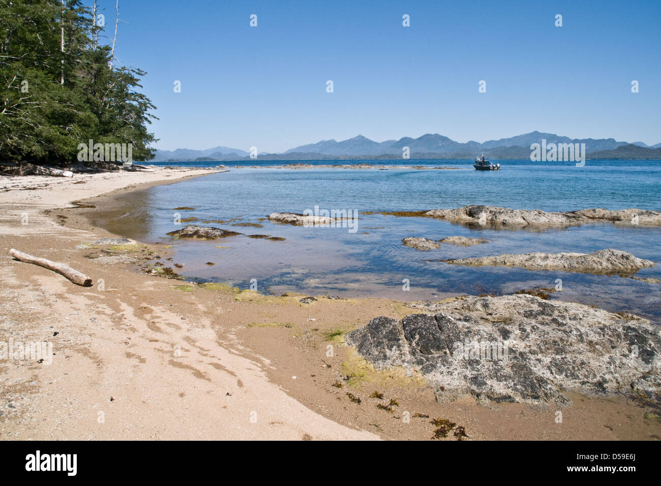 A boat off a sandy beach on the west coast of Swindle Island in the Great Bear Rainforest, British Columbia, Canada. Stock Photo