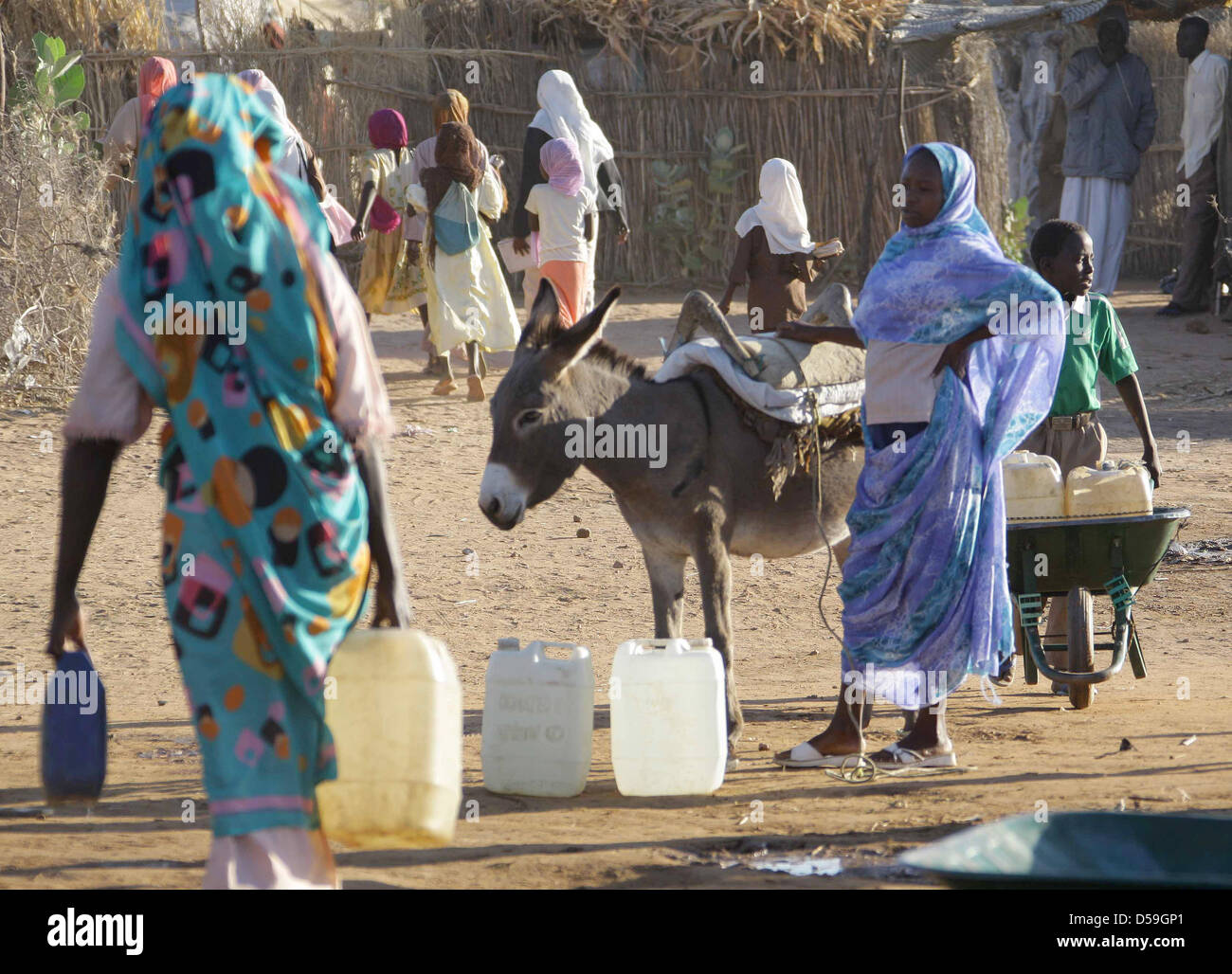 ARCHIV - Mit vollen Wasserkanistern laufen Frauen und Kinder im Flüchtlingslager in der Stadt Nyala in Darfur im Sudan von der Wasserstelle zu ihren Hütten zurück.  (Archivfoto vom 12.12.2007). Im Lager leben 35 000 Binnenvertriebene. Die beiden in der westsudanesischen Krisenregion Darfur entführten Mitarbeiter des Technischen Hilfswerks (THW) kommen aus Berlin und Schleswig-Holst Stock Photo