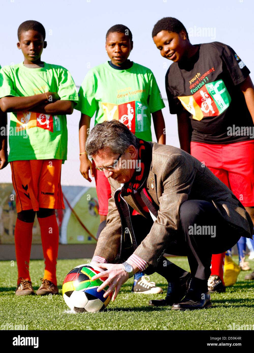 German interior minister Thomas de Maiziere prepares for a penalty kick watched by young South African football players during the opening of a football pitch at the Orange Farm township, about 30km south of Johannesburg, South Africa on 27 June 2010. De Maiziere is on a three-day visit to South Africa. Photo: Kerim Okten  +++(c) dpa - Bildfunk+++ Stock Photo