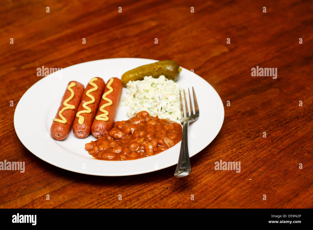 A lunch of franks and beans with cole slaw and a pickle Stock Photo