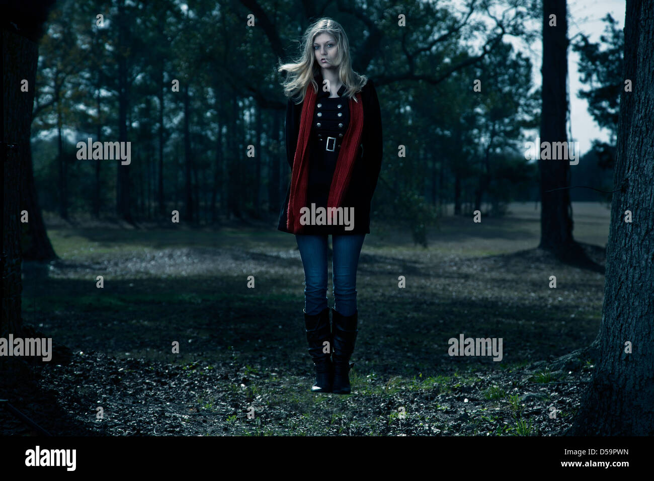 Blond woman black coat red scarf floating outdoors woods blue sky Stock Photo