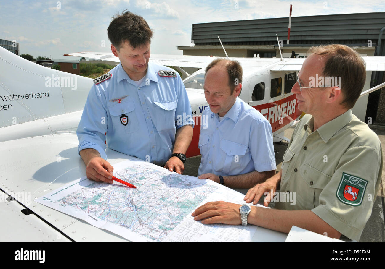 Fireman Joerg Buchholz, pilot Michael Schwan and  forest ranger Michael Friebe (L to R) consult a map before taking off in a Cessna 206 to survey fire hazards in Lueneburg, Germany, 02 July 2010. The fire department's air service surveyed  administrative districts Lueneburg, Luechow-Dannenberg, Uelzen, Soltau-Fallingbostel and Harburg from the air because of an increased risk of fo Stock Photo