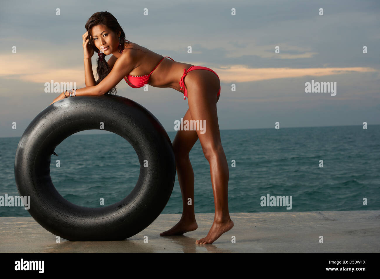Beautiful, happy Asian model wearing red bikini on Thailand beach with tube  from tire Stock Photo - Alamy