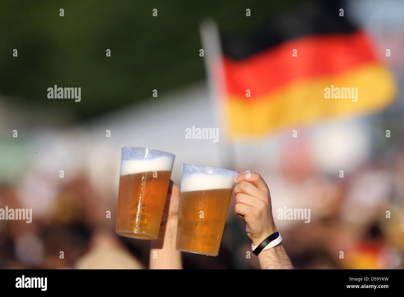 Das Bier in die Höhe haltend kämpft sich ein Fußballfan am Mittwoch (07.07.2010) vor Spielbeginn auf dem Fanfest in Nürnberg durch die Menschenmenge. Die deutsche Fußballnationalmannschaft spielt gegen Spanien im Halbfinale der Fußball-WM in Südafrika. Foto: Daniel Karmann dpa/lby Stock Photo