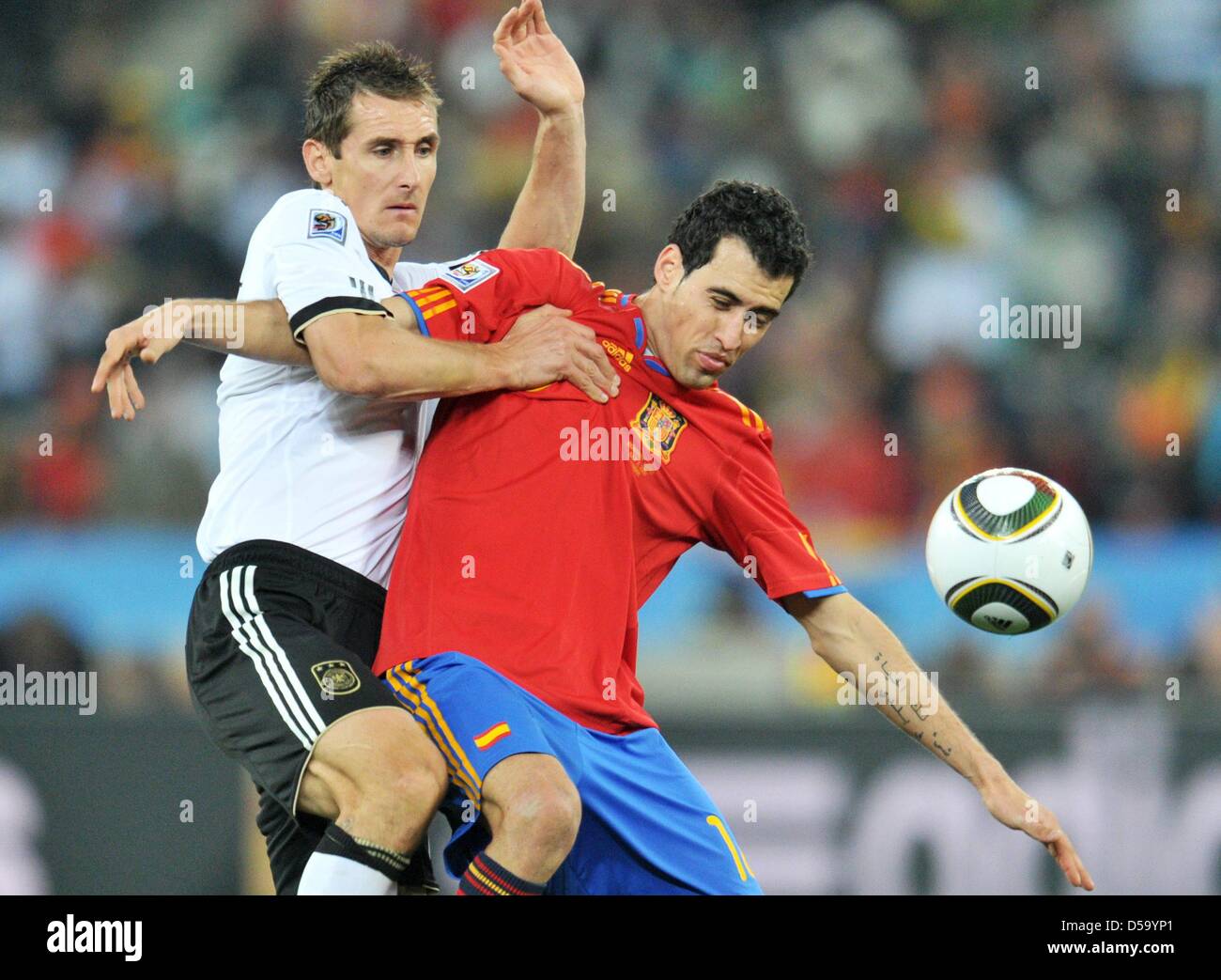 Miroslav Klose (L) of Germany vies with Sergio Busquets of Spain during the 2010 FIFA World Cup semi-final match between Germany and Spain at the Durban Stadium in Durban, South Africa 07 July 2010. Photo: Bernd Weissbrod dpa - Please refer to http://dpaq.de/FIFA-WM2010-TC Stock Photo