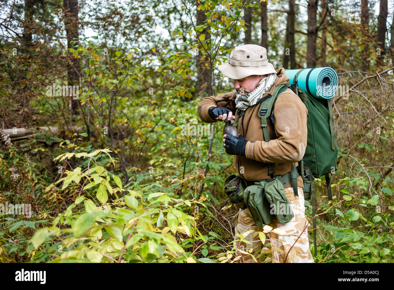 Soldier in a forest with water-bottle. Stock Photo