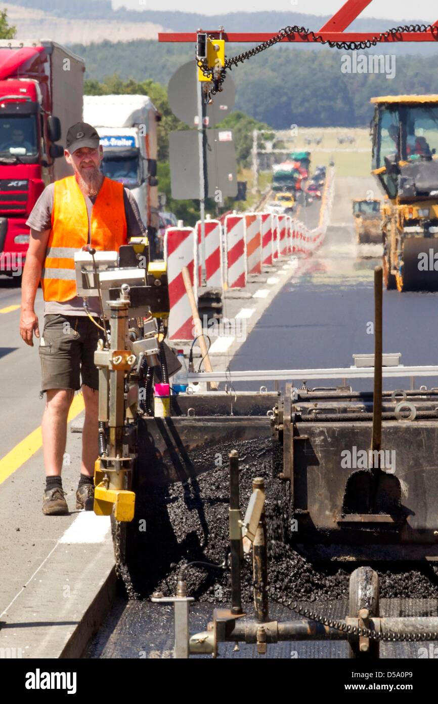 Construction worker Ulf Schaefer adjusts the thickness of the asphalt in the machine as the autobahn A4 is bituminised between Jena and Stadtroda towards Dresden, Germany, 08 July 2010. The construction work is part of a pilot project testing the new method of 'Prozesssicherer Automatisierter Straßenbau' on the heavily frequented roadway. The project applies new methods of asphalti Stock Photo
