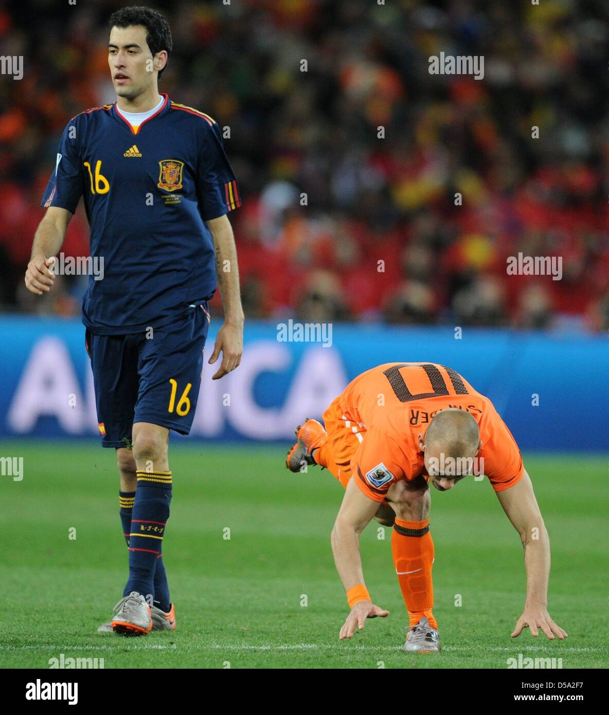 Dutch Wesley Sneijder (R) goes to the ground next to Spain's Sergio Busquets during the 2010 FIFA World Cup final match between the Netherlands and Spain at Soccer City Stadium in Johannesburg, South Africa 11 July 2010. Photo: Marcus Brandt dpa - Please refer to http://dpaq.de/FIFA-WM2010-TC  +++(c) dpa - Bildfunk+++ Stock Photo