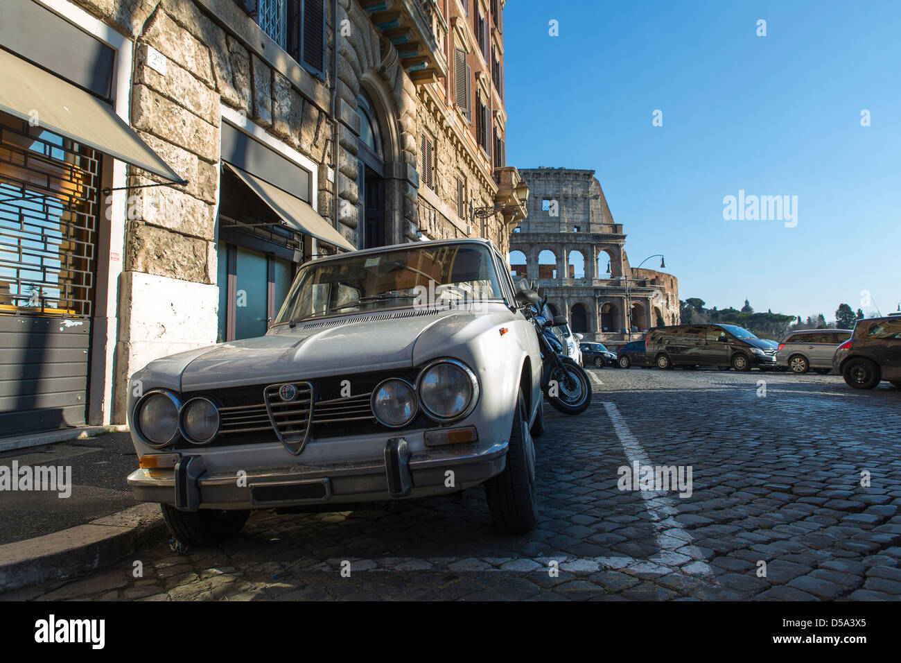 Old white Alfa Romeo car parked by the Roman Colosseum in Rome Italy Stock Photo