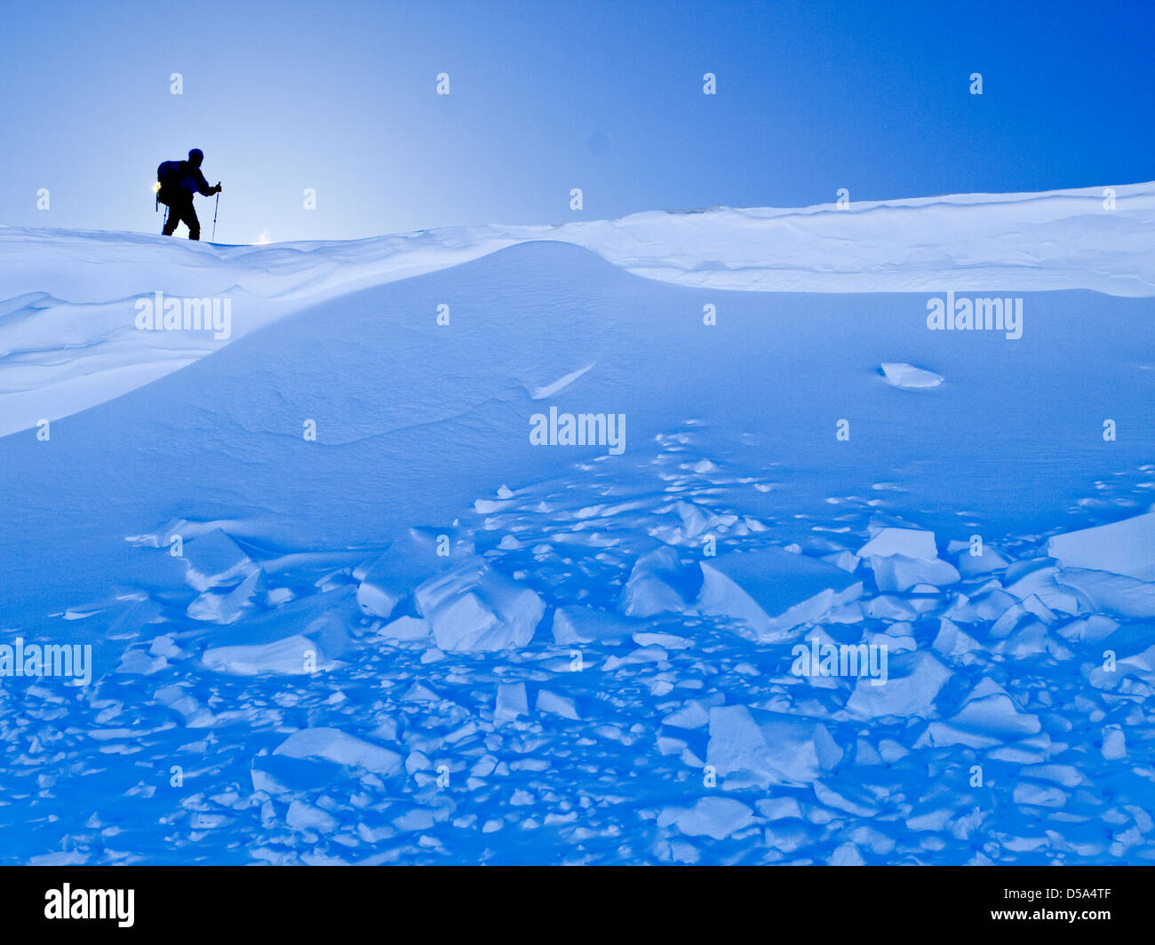 Ski touring in Northern Norway a skier at the top of a slope with avalanche debris below Stock Photo