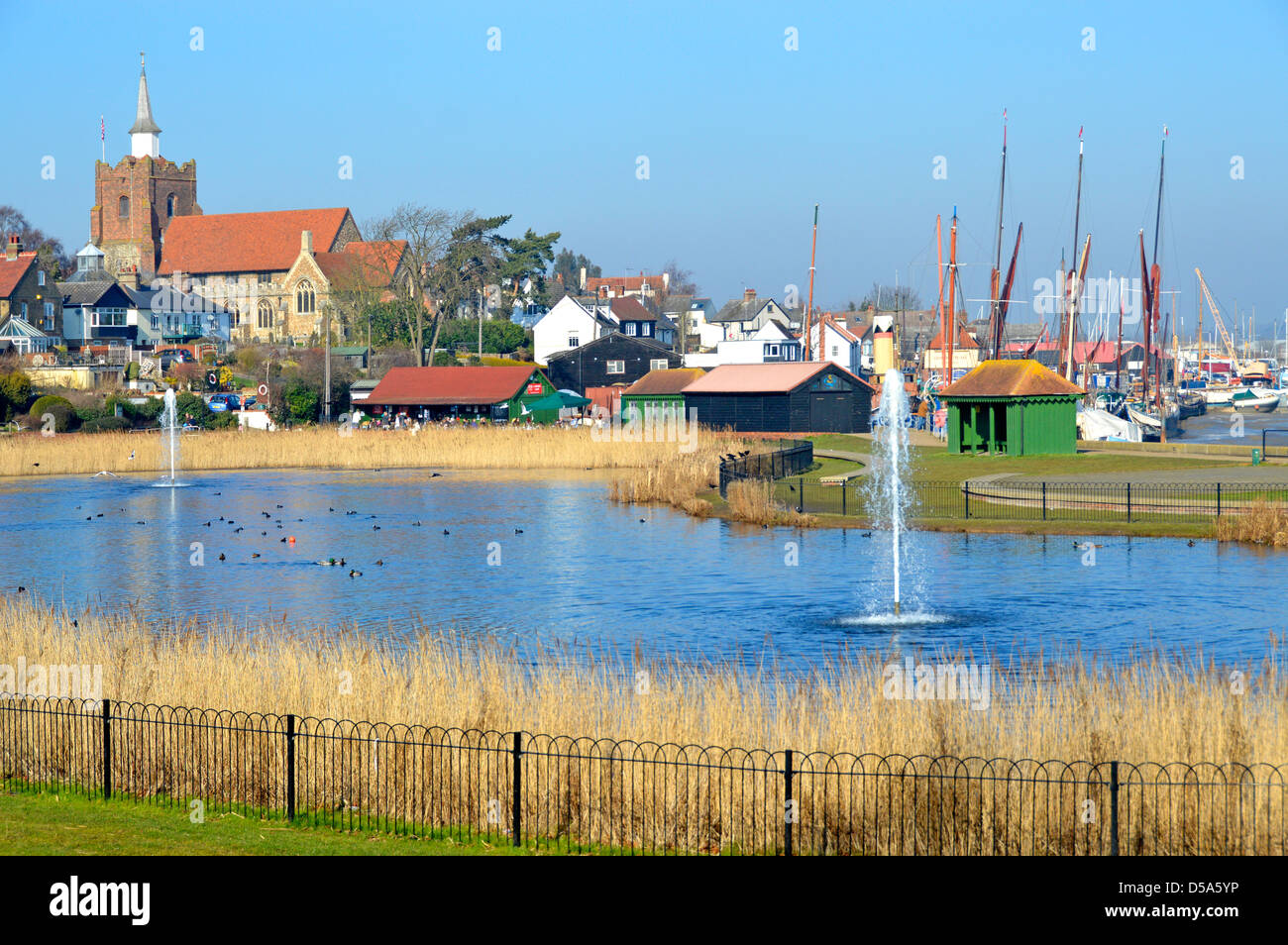 Pond & fountain landscape in Promenade Park adjoins River Blackwater estuary church & masts of Thames sailing barges beyond in Maldon Essex England UK Stock Photo