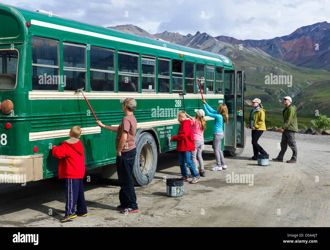 Young park visitors help clean the dust from the shuttle bus windows, Eielson Visitor Center, Denali National Park, Alaska, USA Stock Photo