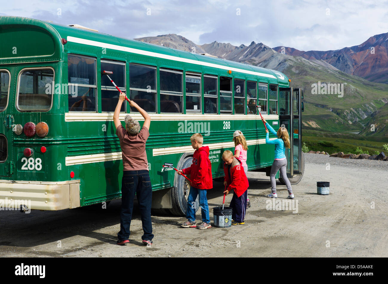 Young park visitors help clean the dust from the shuttle bus windows, Eielson Visitor Center, Denali National Park, Alaska, USA Stock Photo