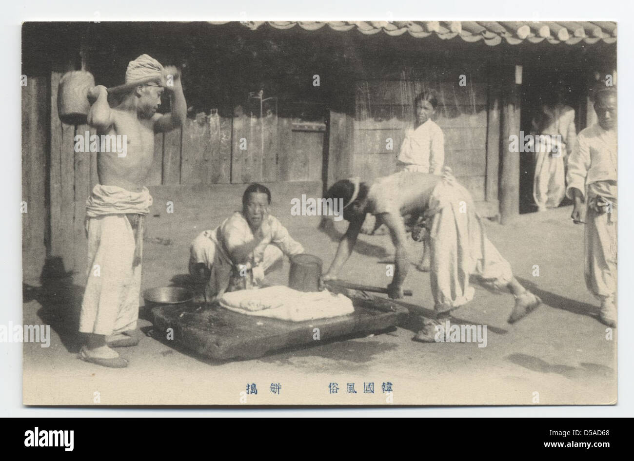 A photograph depicting the process of pounding rice cake, a traditional ...