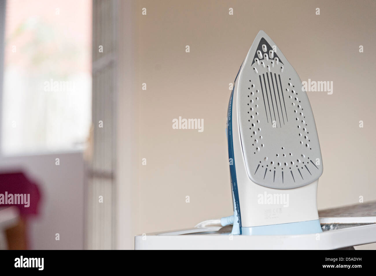 an iron sitting on an ironing board ready to iron a house holds clothes