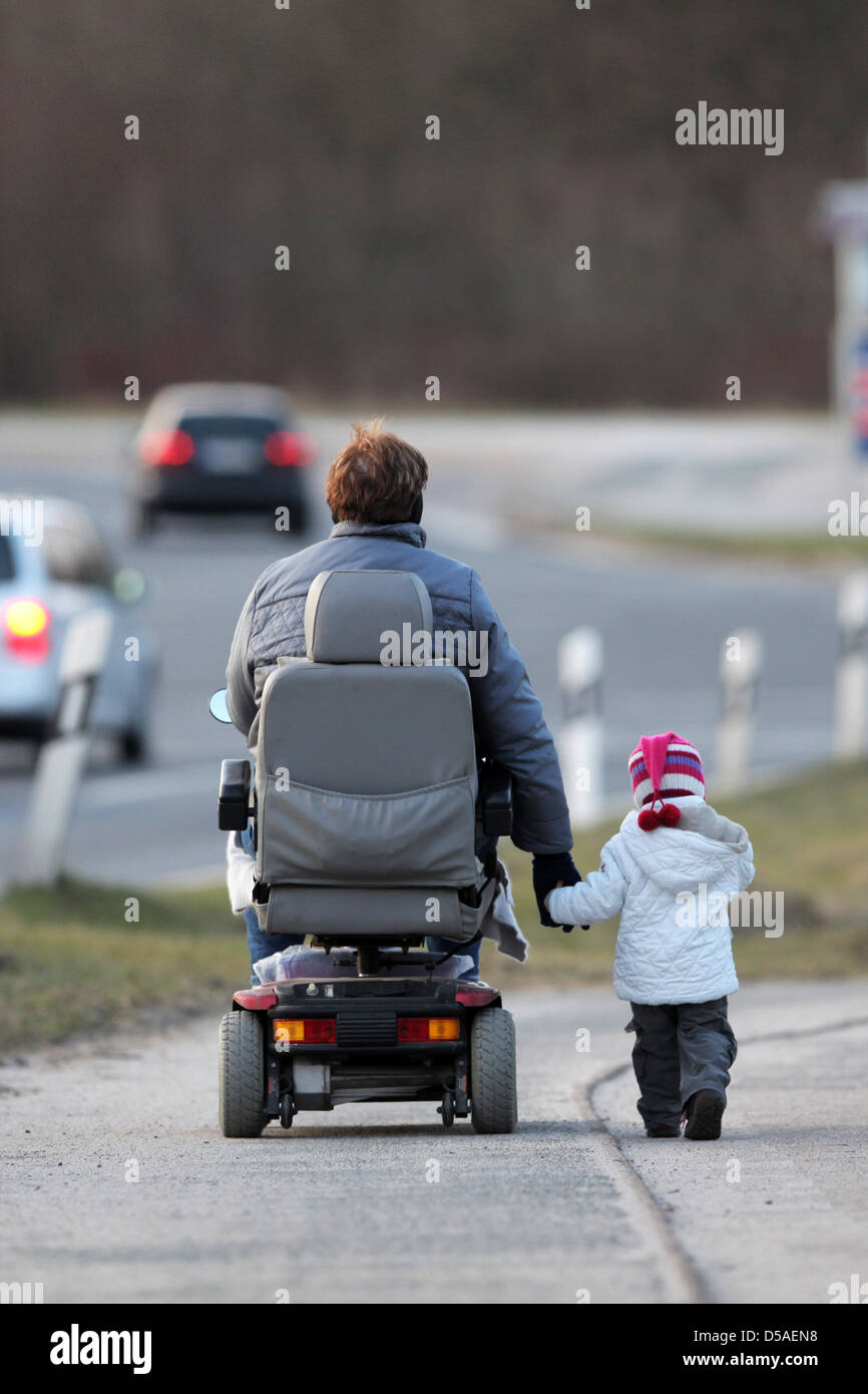 Handewitt, Germany, a grandmother RUNNING walk in an electric wheelchair with her grandson's hand on a bicycle Stock Photo