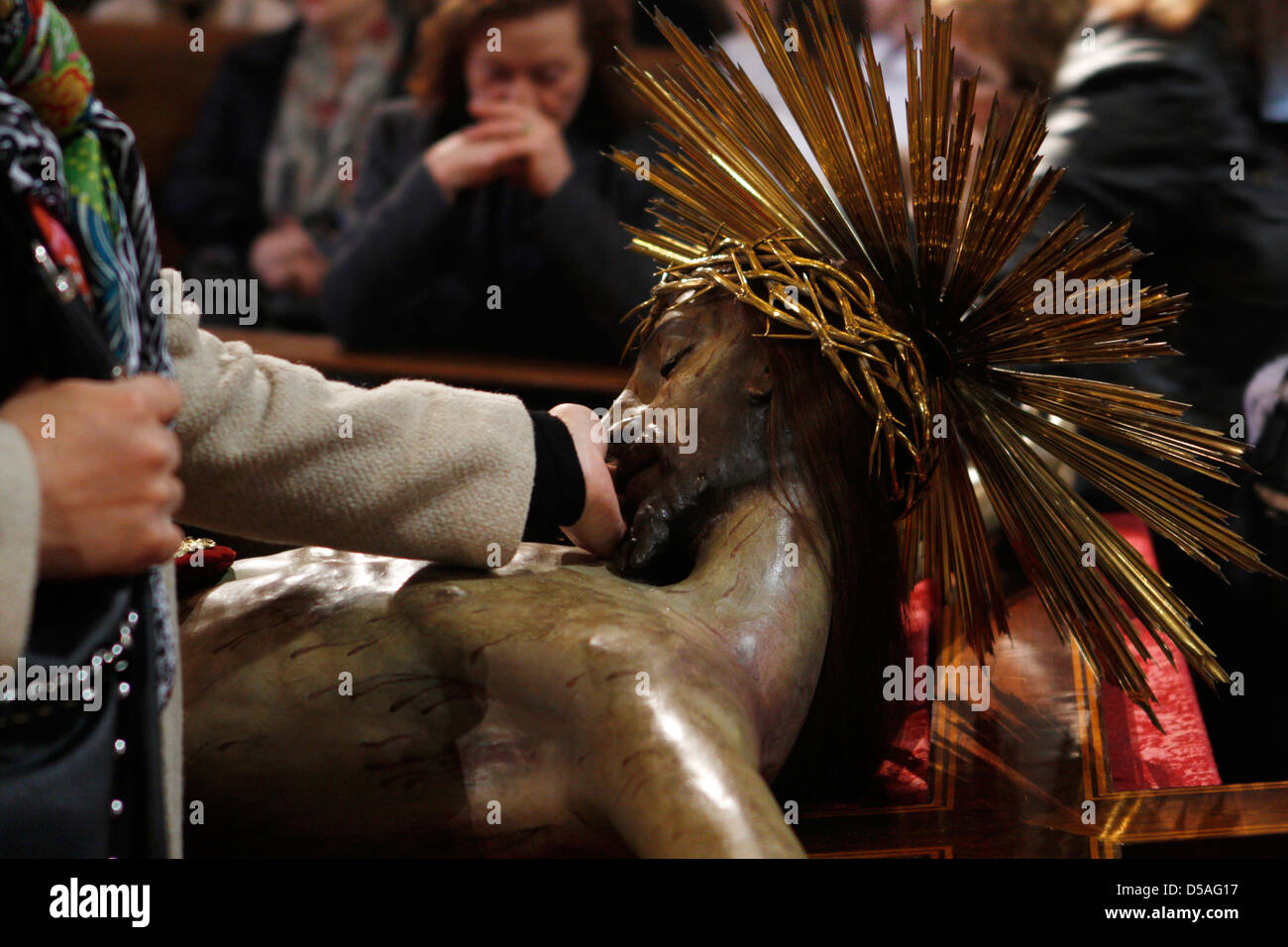 People pray near a statue representing Christ inside a church during easter week in Spain Stock Photo