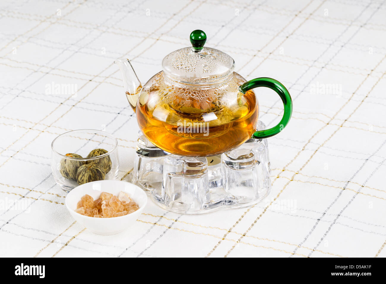 Horizontal photo of glass tea pot, holder and tea balls, sugar in bowl,  with White Striped Table Cloth in background Stock Photo - Alamy