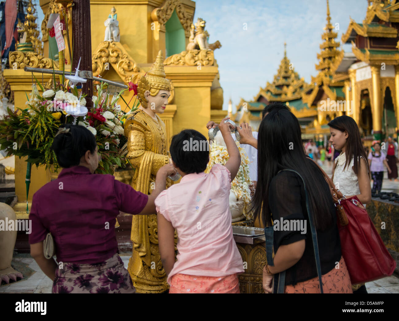Buddhist worshipers poor water over Buddhas to wash away their own sins. Stock Photo