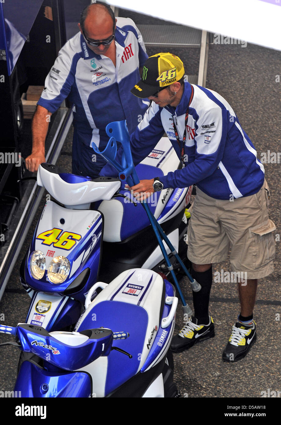 The Italian Yamaha driver and MotoGP superstar Valentino Rossi uses his  crutches to descend from a scooter in the paddock at the German Motorcycle  Grand Prix on the Sachsenring in Hohenstein-Ernstthal, Germany,