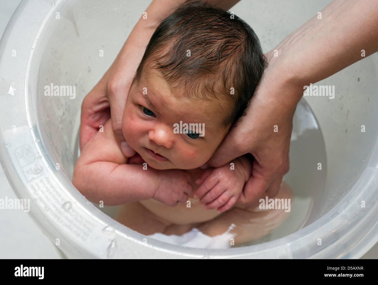 A mother places her baby in a special 'bath bucket' in Sieversdorf,  Germany, 18 July 2010. The bath bucket's from makes the baby assume a  posture similar to the one it had