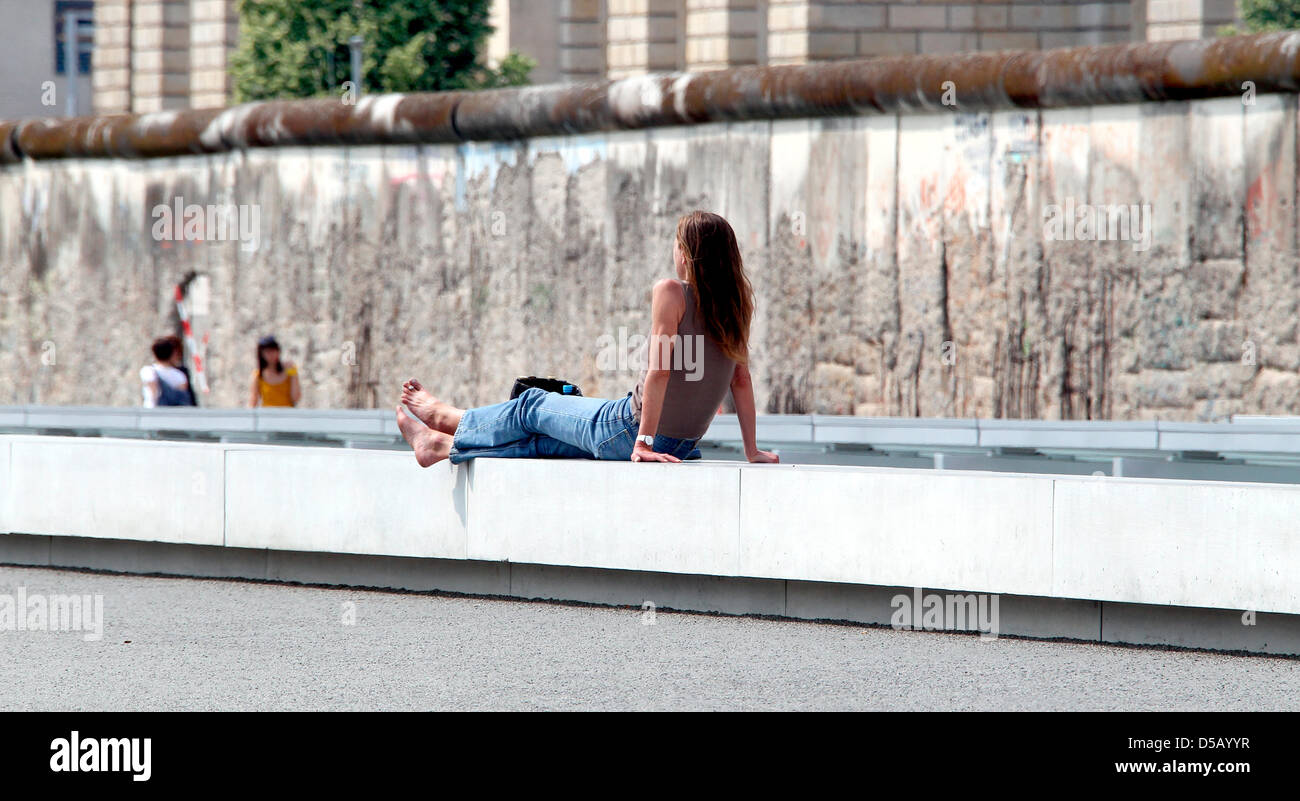 A woman takes a sunbath nearby maintained parts of the Berlin Wall on the grounds of the former headquarters of the German Third Reich Secret Police 'Gestapo' which now belongs to the exhibition 'Topography of Terror' at Niederkirchner Street in Berlin, Germany, 28 July 2010. Photo: Wolfgang Kumm Stock Photo
