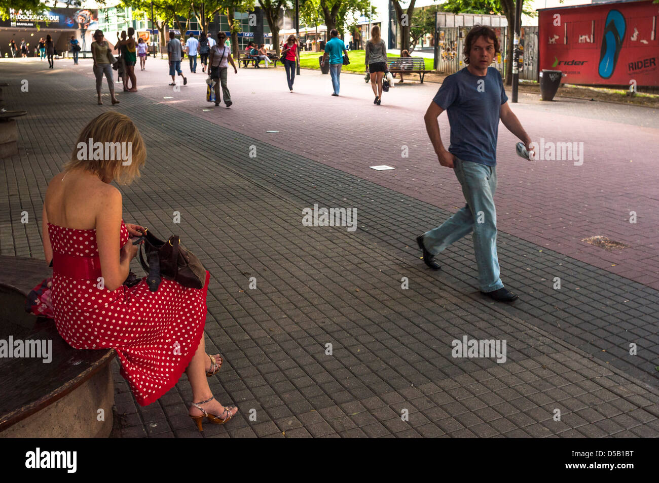 man walking around a woman in red wihte dotted dress in summer street Stock Photo