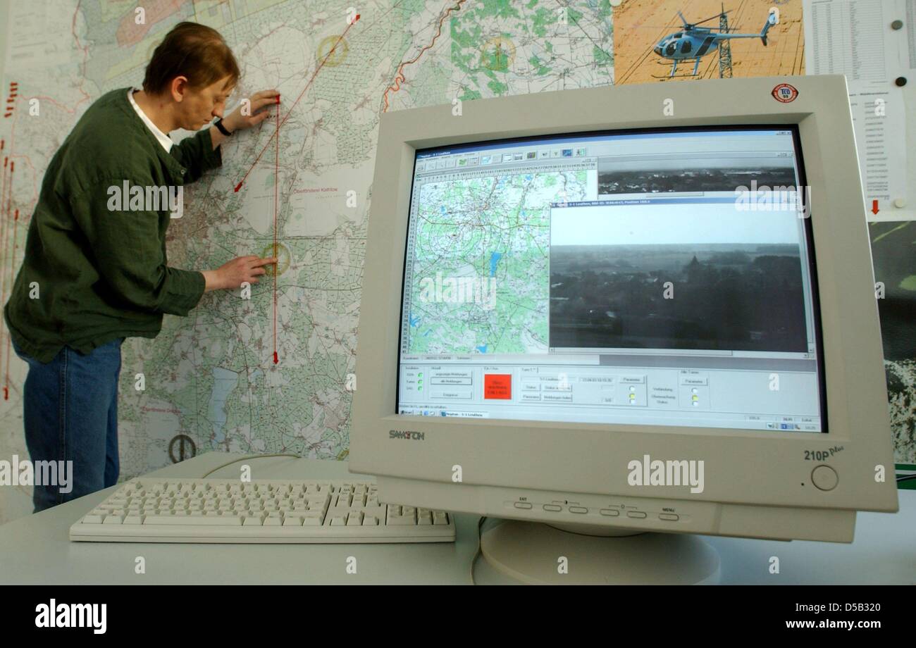 (dpa FILE)- A picture dated 23 April 2003 shows the forest manager Bernd Stripp indicating the location of a forest fire on a map in the forest fire headquarters, while a monitor presents pictures from watchtowers, Germany. The camera system 'Fire Watch'in Brandenburg has become an export hit, since experts from around the world visited Brandenburg to sea how one can save lives fro Stock Photo