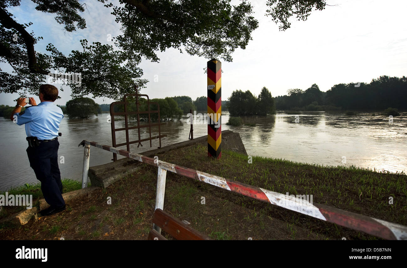A policeman takes a photograph of the high water on the Neisse at a dike in Klein Bademeusel, Germany, 09 August 2010. The town was the first to be evacuated due to the high waters on the Neisse and Spree rivers. Photo: Arno Burgi Stock Photo