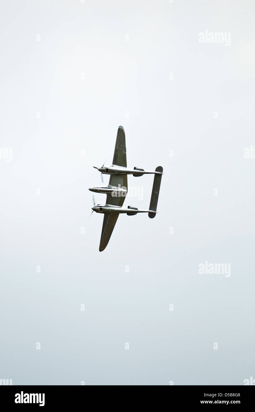 Portrait image of a World war two vintage fighter plane flying over head, isolated against a grey sky. Stock Photo