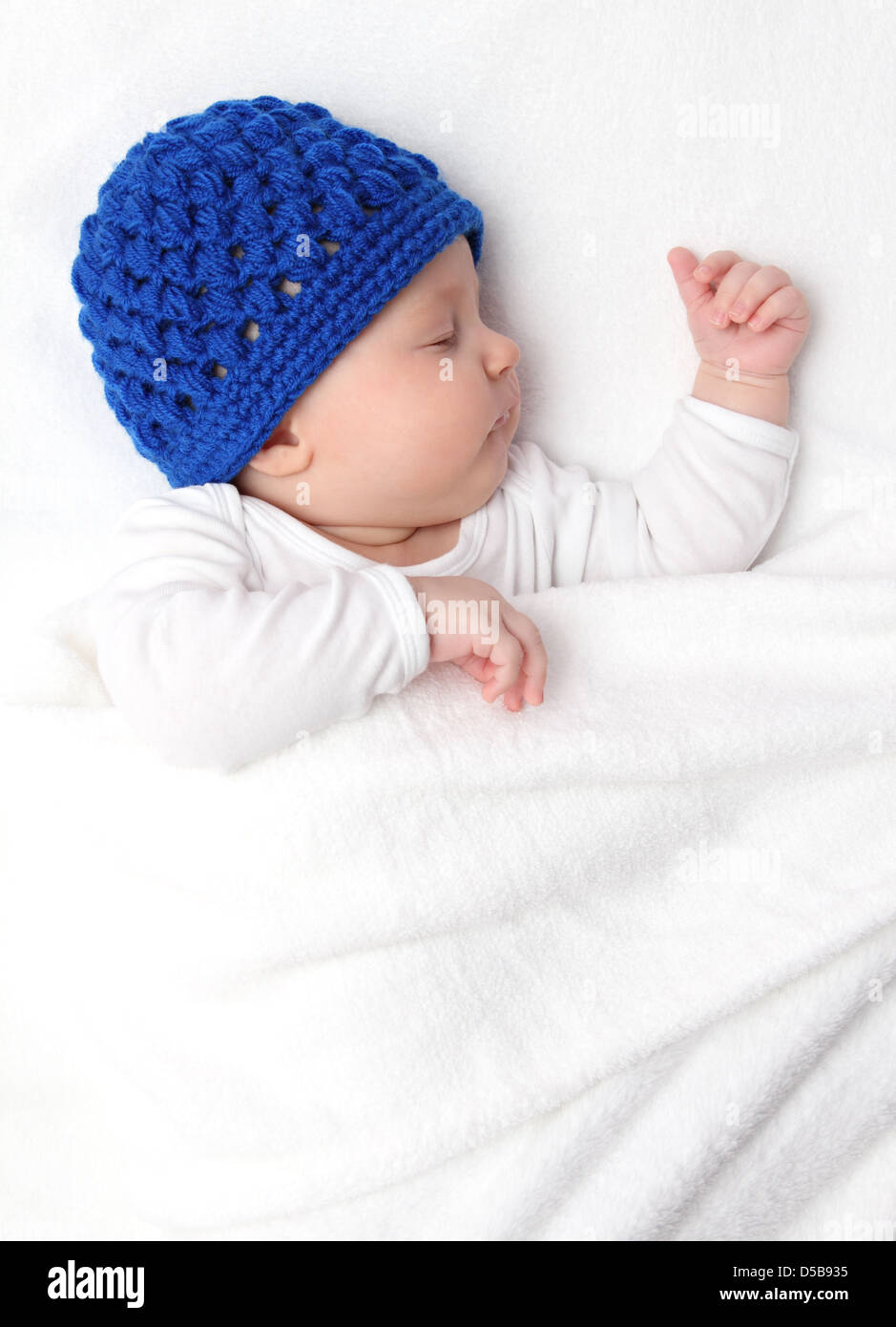 Beautiful baby sleeping on bed under a white blanket Stock Photo