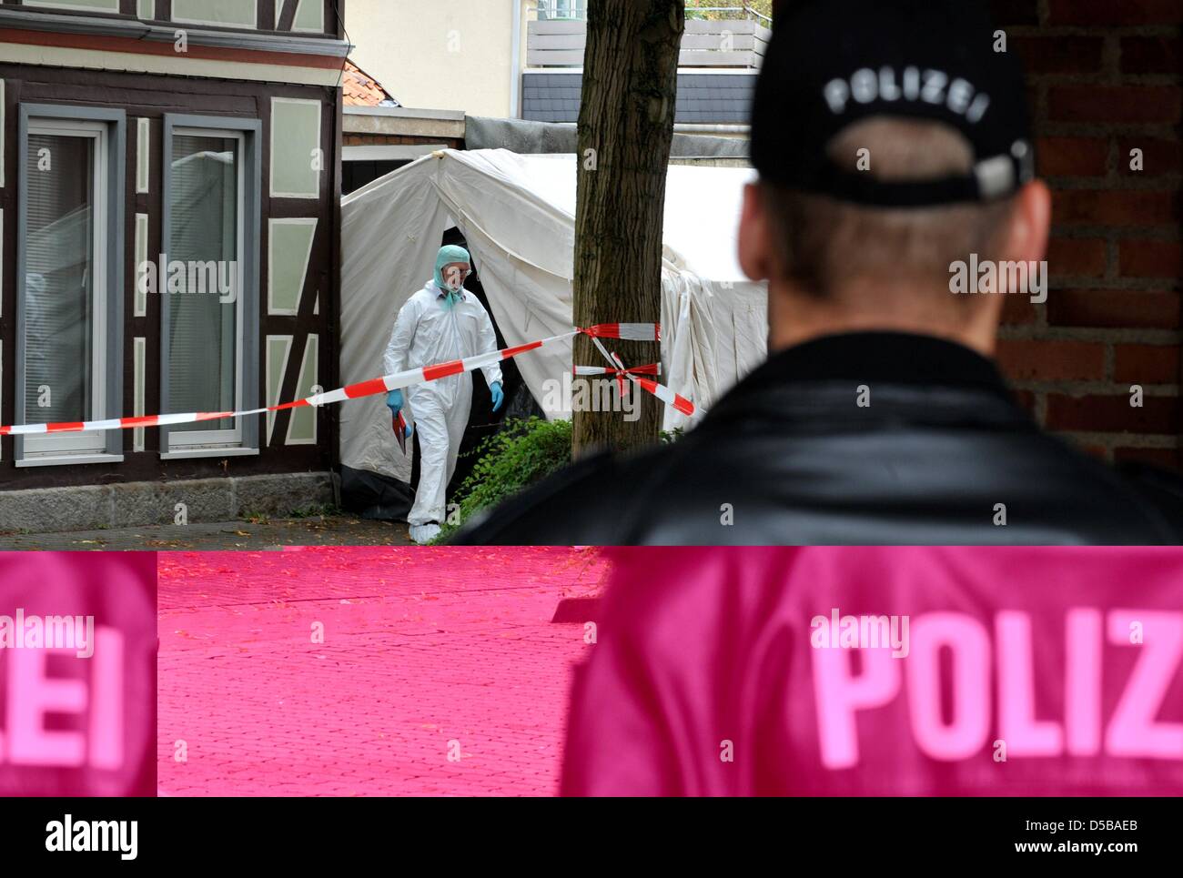 A policeman secures the site of discovery of a five year old dead boy in Dellingen (district Holzminden), while a crime investigator leaves a tent, Germany, 18 August 2010. The corpse was found in a garage next to the home of the mother. The five year old child was missing since Tuesday afternoon (17 August). Photo: Jochen Luebke Stock Photo