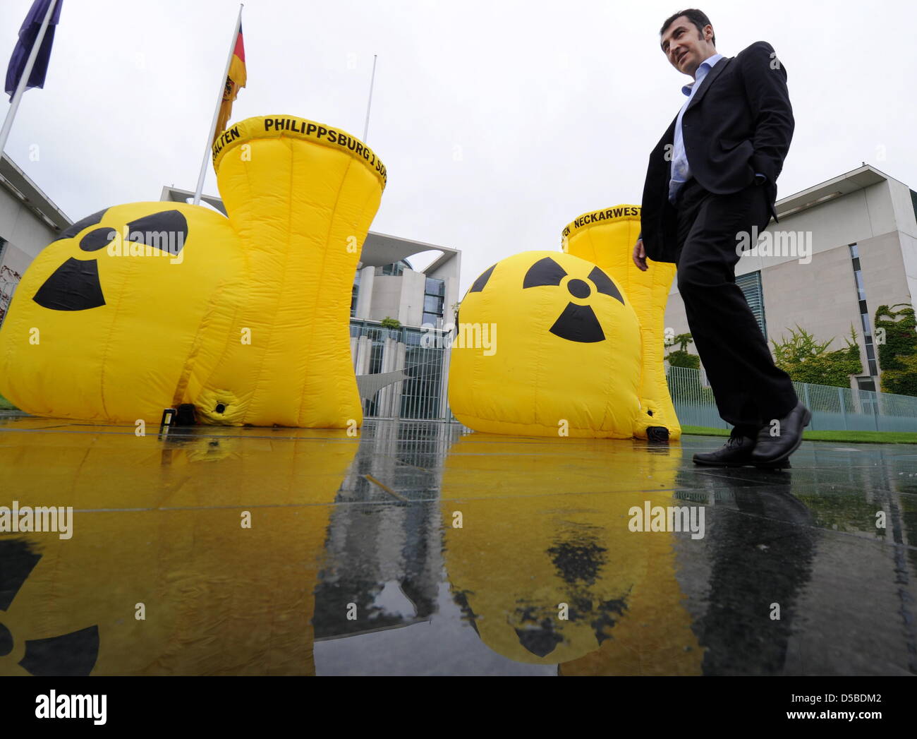 Greens chairman Cem Oezdemir is about two deflate two rubber nuclear plants in front of the German Chancellery after stating his views on nuclear policy with head of the parliamentary fraction Renate Kuenast in Berlin, Germany, 27 August 2010. Photo: TIM BRAKEMEIER Stock Photo