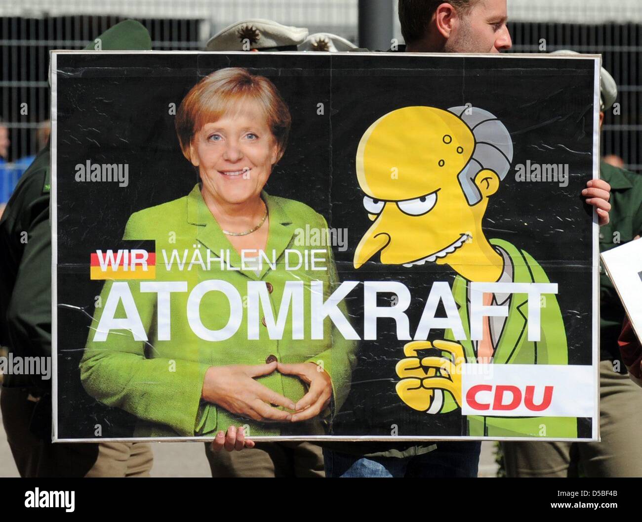 A protestor holds up a banner comparing German Chancellor Merkel with The Simpsons character Montgomery Burns as Mrs Merkel visits plant manufacturer Voith in Heidenheim, Germany, 27 August 2010. Mrs Merkel is on a so-called energy trip through Germany visiting various power plant facilities. Photo: Marijan Murat Stock Photo