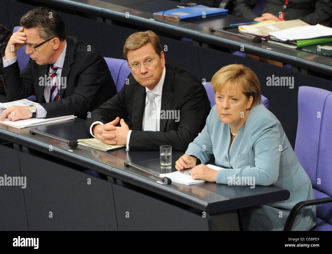 (L to R) German Interior Minister Thomas de Maiziere,  Foreign Minister and Vice Chancellor Guido Westerwelle and Chancellor Angela Merkel attend a Bundestag (German Parliament) session at the Reichstag in Berlin, Germany, 14 September 2010. The German Parliament is discussing the controversial 2011 budget, which entails spending cuts adding up to 12 billion euros, mainly in social Stock Photo