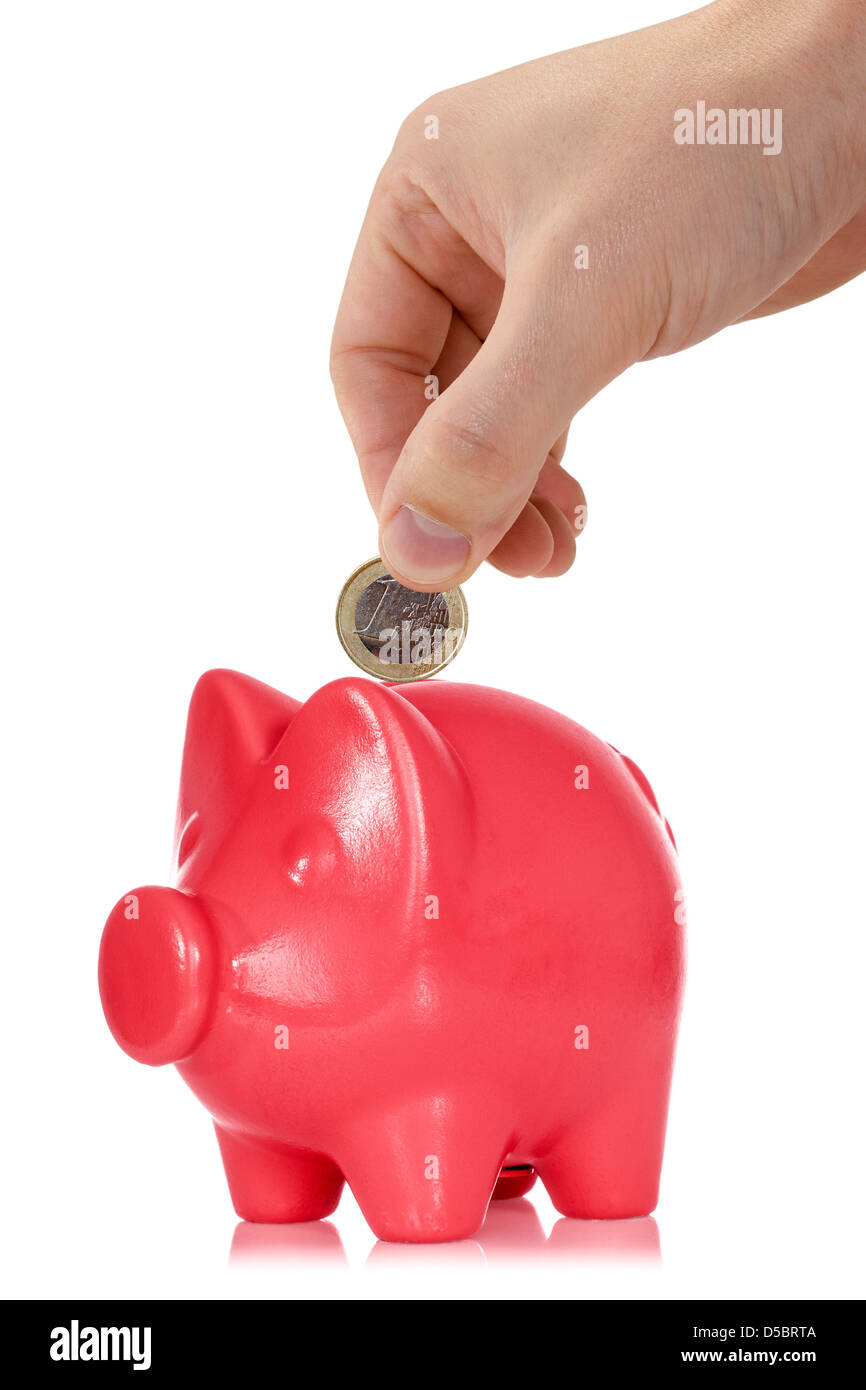 Hand putting one Euro coin into the piggy bank Stock Photo - Alamy