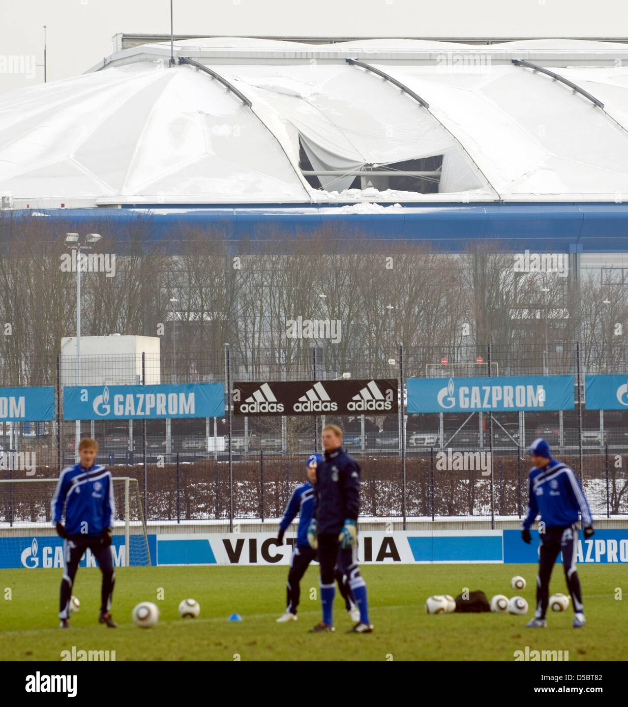 Players of German Bundesliga soccer club FC Schalke practice on an outdoor pitch in front of Veltins Arena with a damaged roof in Gelsenkirchen, Germany, 13 January 2010. The hole could cause the Bundesliga match FC Schalke vs FC Nuremberg, which is due to take place on 17 January 2010 at VeltinsArena, to be postponed. Photo: BERND THISSEN Stock Photo